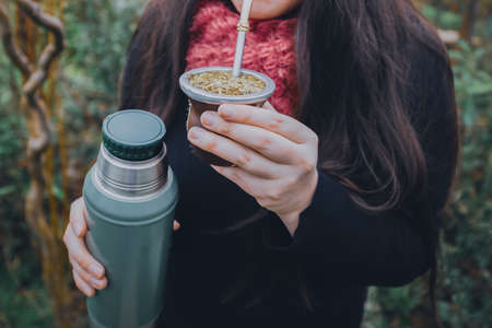 Young woman drinking mate in the park. Latin beverage.