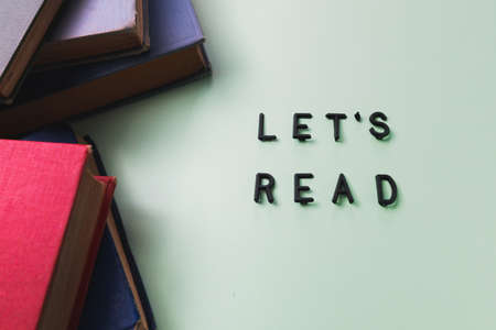 Old books over a pale green backdrop, and a lets read messageの写真素材