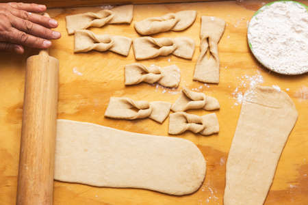 Old womans hands kneading dough on a wooden table. Chilean fried pastries. Latin food.
