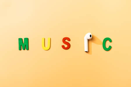 the word music on wooden color letters, with a wireless earphone replacing the letter i.の写真素材