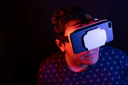 Young latin man using Virtual Reality VR Headset 3D Glasses. Studio dark backdrop. Low key.の写真素材
