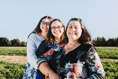 Grandmother, mother and daughter smiling in the middle of the field on a sunny day afternoon. Family...