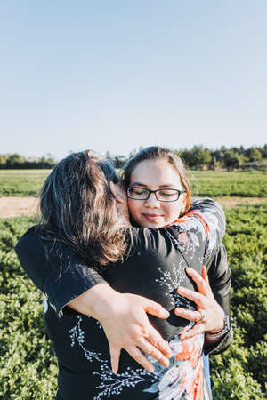Mother and daughter walking and hugging in the middle of the field on a sunny day afternoon. Family...