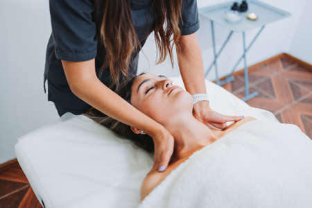 Female therapist making a neck and shoulders massage to a face up female patient. Relaxing an de-stressの写真素材