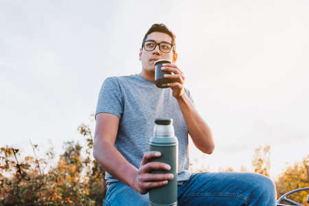 Latin farmer man drinking mate and relaxing, in a rural space, on top of an old little tractor. Hot...