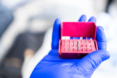 Dentists hand with blue rubber glove on, holding a composite polishing kit. Stomatology concept....