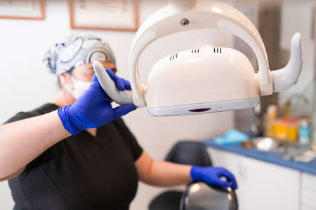 Female dentist preparing dental chair lightの写真素材