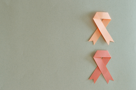 Duo of leukemia and uterus cancer ribbon made with paper on beige background.の写真素材