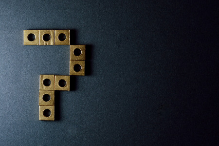 Golden mechanic nuts forming shapes and numbers on dark background.の写真素材