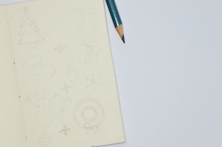 Square sketchbook with handmade drawings of Christmas items, pencil line style on white background.の写真素材