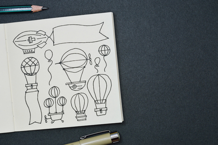 Square sketchbook with handmade drawings of hot air balloons, black and white line style.の写真素材