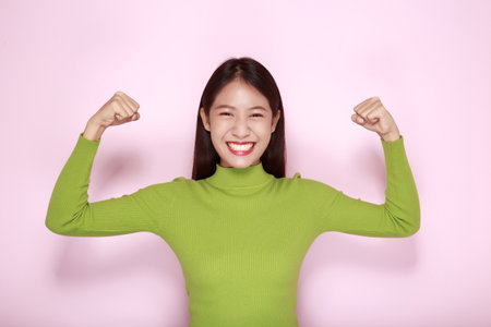 Portrait of a beautiful young woman in a light pink background, happy and smile, posting in stand...