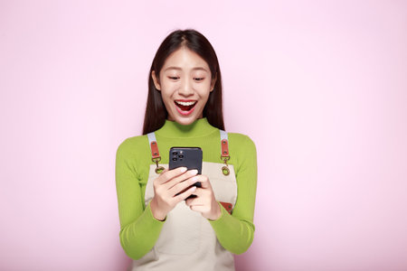 Asian woman looks surprised while holding phone in hand, Portrait of a beautiful young woman in a...