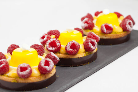 cakes with jelly and raspberry on a black plateの写真素材