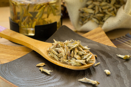 Dry White Tea on the wooden spoon, teapot and a burlap sack in the backgroundの写真素材