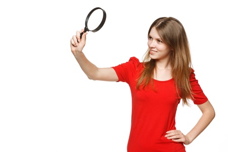 Young female student looking through the magnifying glass, isolated on white backgroundの写真素材