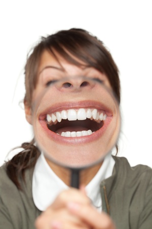 Funny image of female with magnifying glass showing teeth over white backgroundの写真素材