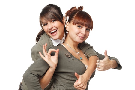 Two excited girls showing OK signs, isolated on white backgroundの写真素材