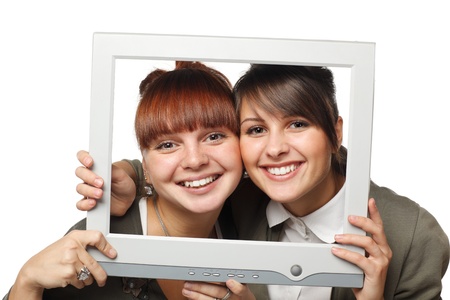 Two excited girls looking through the old fashioned computer screen, isolated on white backgroundの写真素材
