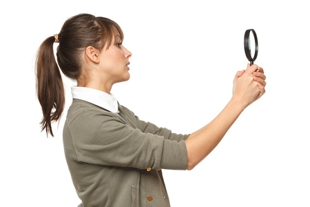 Side view of young female looking with magnifying glass, over white backgroundの写真素材