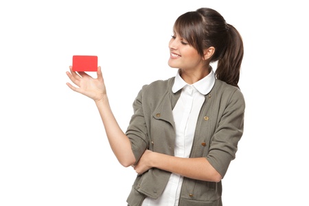 Close-up portrait of young smiling business woman holding credit card and and looking at it isolated on white backgroundの写真素材