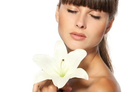 Closeup portrait of beautiful woman with closed eyes holding a lily flowerの写真素材