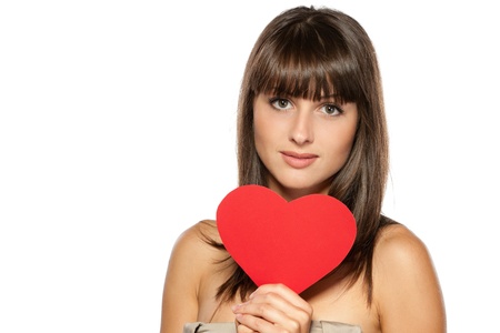 Closeup portrait of young female holding heart shape isolated on white background, with copy-spaceの写真素材