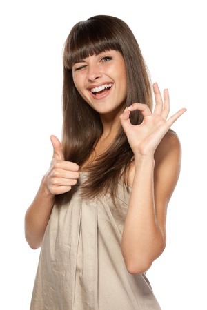 Young attractive female with thumbs-up and OK gesture isolated on whiteの写真素材