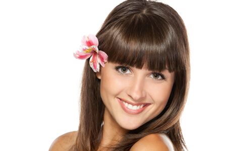 Closeup portrait of young beautiful female with flower over her ear, isolated on white backgroundの写真素材
