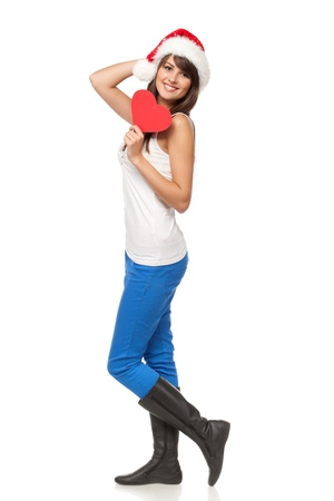 Ful length of young female in casual wearing Santa hat holding heart shape, isolated on white backgroundの写真素材