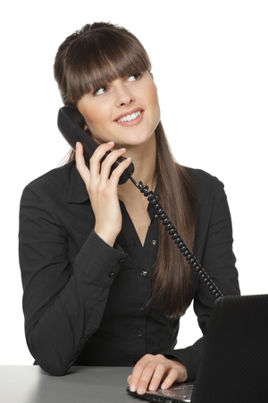 Smiling business woman talking on the phone at her work desk looking upwards, isolated on white backgroundの写真素材