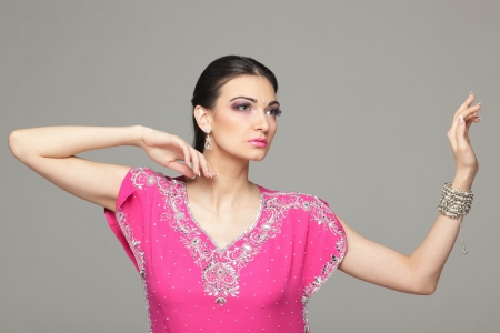 Fashion portrait of beautiful female wearing traditional indian costume, over grey backgroundの写真素材
