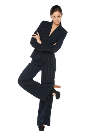Full length portrait of young business woman standing with folded hands and crossed legs, isolated on white backgroundの写真素材