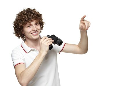 Portrait of a smiling male holding binoculars and pointing at blank copy space, over white backgroundの写真素材
