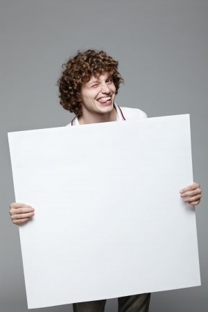 Smiling man holding blank banner over gray backgroundの写真素材