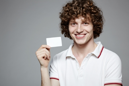 Portrait of the young smiling man holding blank credit card, isolated on gray backgroundの写真素材