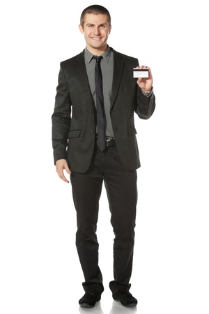 Young smiling businessman holding credit card, isolated on white backgroundの写真素材
