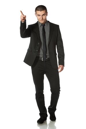 Full length of young business man in suit pointing at copy space over white backgroundの写真素材