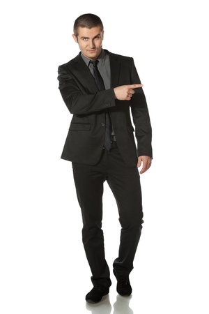 Full length of young business man in suit pointing at copy space over white backgroundの写真素材