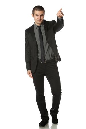 Full length of young business man in suit pointing at copy space over white backgroundの写真素材