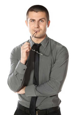 Pensive young  businessman holds a pair of glasses, isolated on white backgroundの写真素材