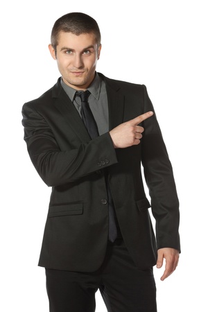 Young business man in suit pointing at copy space over white backgroundの写真素材