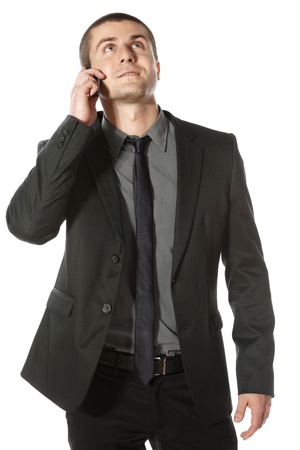 Youngbusinessman talking on cell phone looking upwards isolated on white backgroundの写真素材