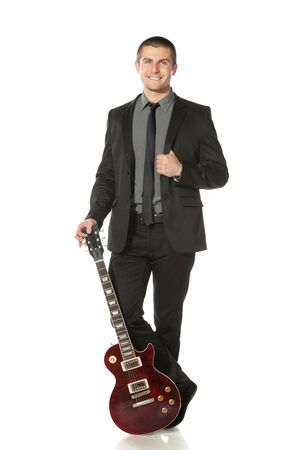 Full length of young man in a suit standing leaning on the guitar over white backgroundの写真素材