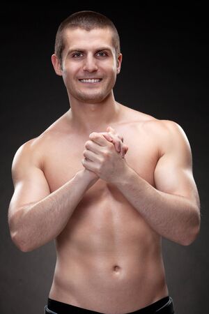 Handsome male model topless standing over dark backgroundの写真素材