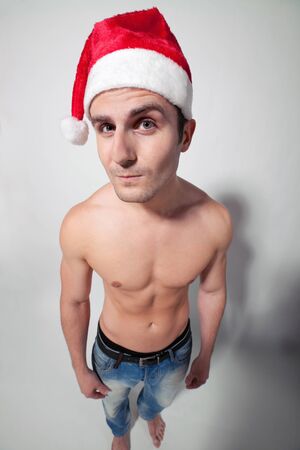 Funny image of muscular shirtless man wearing Santa hat looking at youの写真素材