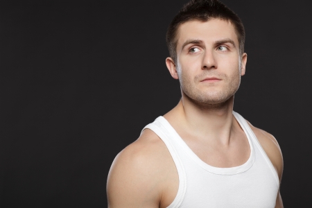 Closeup of handsome muscular man in white t-shirt over dark backgroundの写真素材