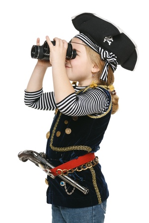 Six years girl wearing costume of pirate looking away through the binoculars, over white backgroundの写真素材