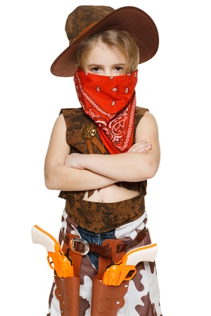 Little serious girl wearing cowboy costume and bandana covering her mouth standing with folded hands, over white backgroundの写真素材