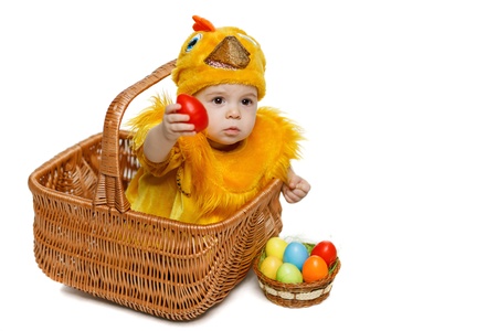 Baby sitting in Easter basket in chicken costume and giving you Easter egg, isolated on white background, with copy space  Easter holiday concept の写真素材